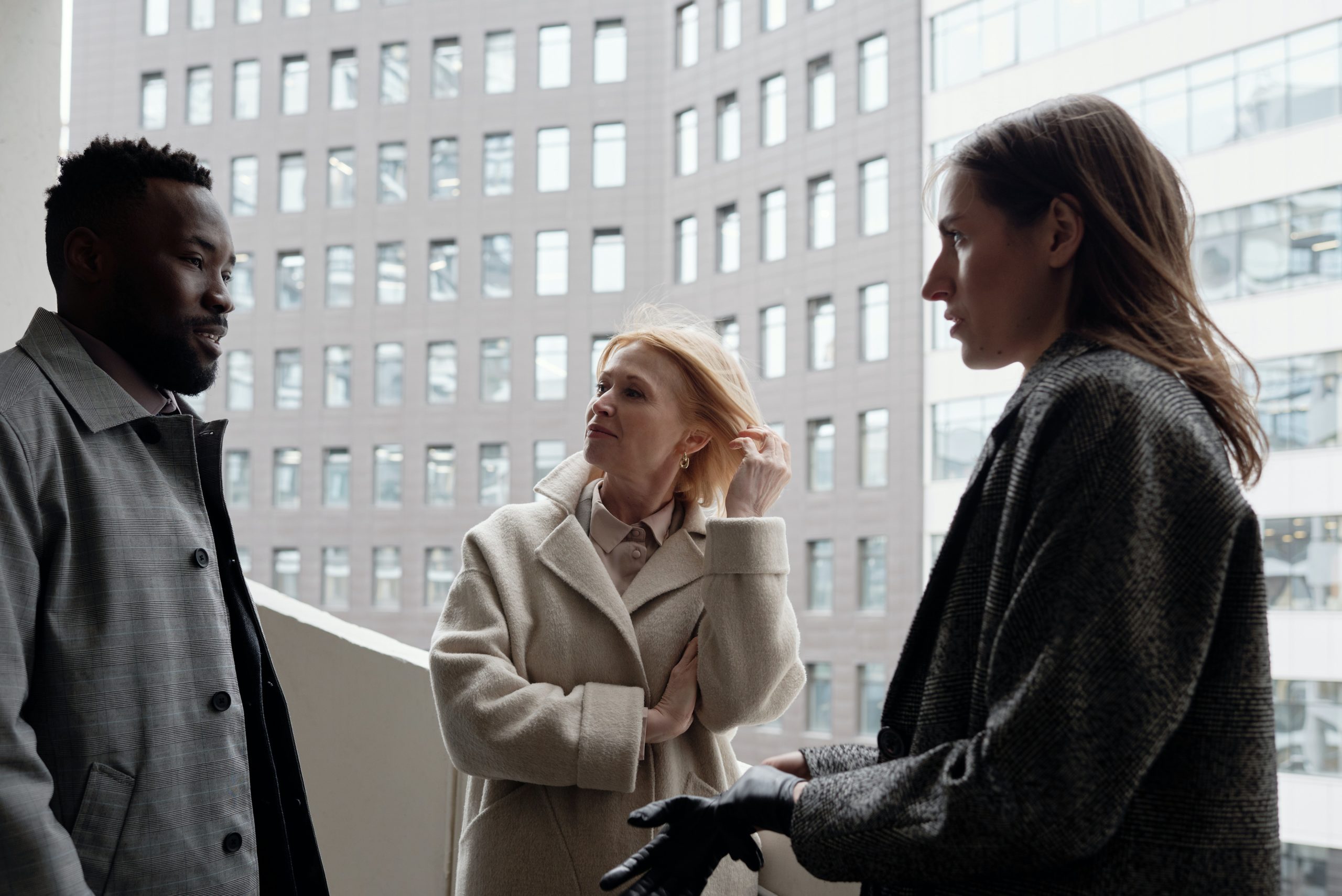 Trois personnes discutant devant un immeuble de bureaux